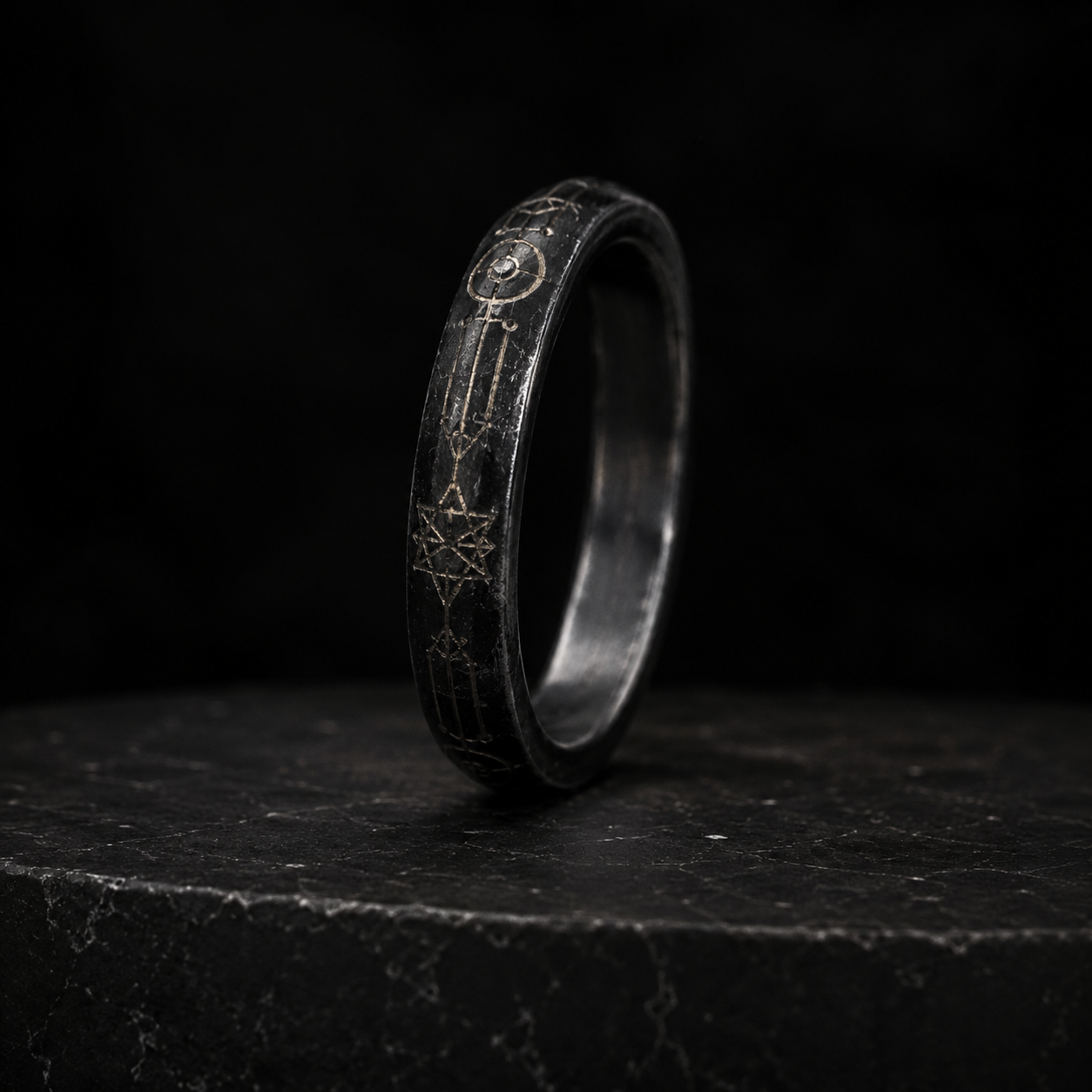A slim black metal ring engraved with fine orbital markings
