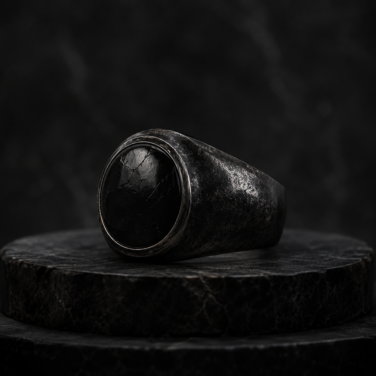 A broad black signet ring with a cracked obsidian face